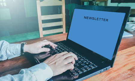 Newsletter concept hand of businessman checking message box on digital laptop vintage tone filter top view