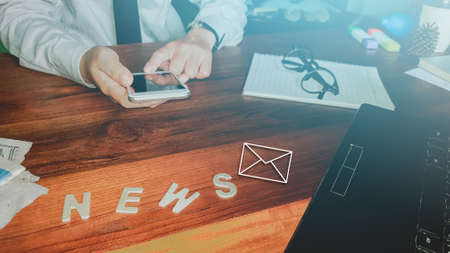 Newsletter concept hand of businessman checking message box on digital mobile phone vintage tone filter top view Stock Photo