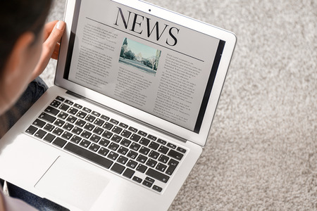 Woman reading news on laptop indoors Stock Photo
