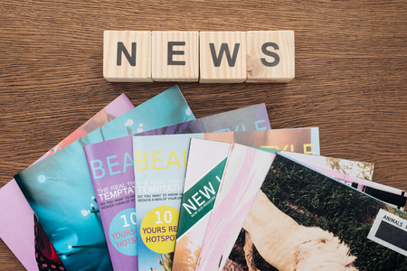Top view of wooden cubes with word news and magazines on wooden tabletop