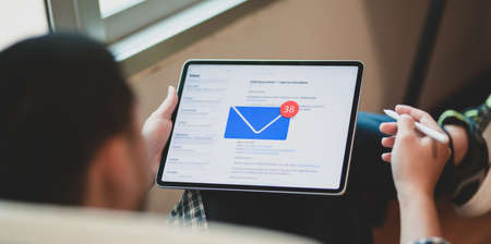 Young businessman checking his email on tablet in comfortable workplace Stock Photo