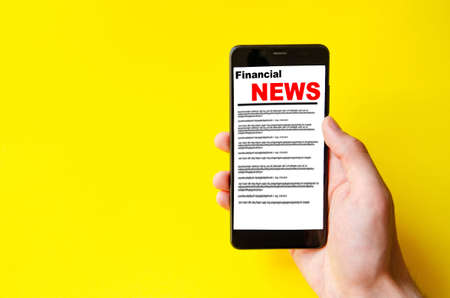 Male hand holds a smartphone on the screen the inscription financial news Stock Photo