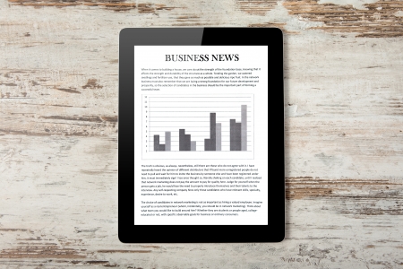 Tablet computer with business news on a screen on a background of wood