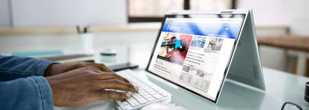 Reading newspaper article on laptop news media