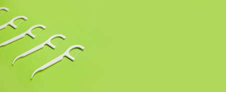 Floss toothpicks on green background with space for text