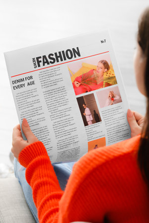 Young woman reading newspaper at home closeup