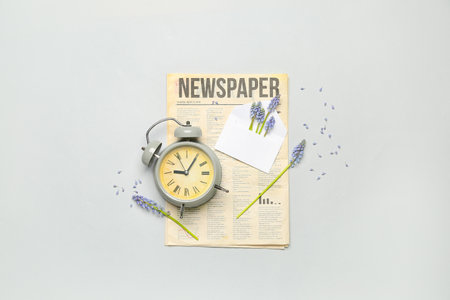 Composition with beautiful muscari flowers alarm clock and newspaper on gray background Stock Photo