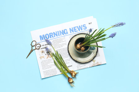 Composition with beautiful muscari flowers newspaper cup and scissors on blue background Stock Photo