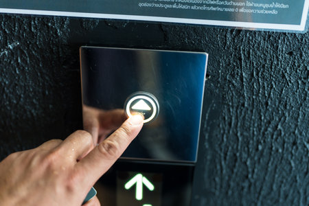 A hand presses a button on an elevator panel Stock Photo
