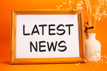 Latest news symbol concept words latest news on beautiful wooden picture frame beautiful orange background with flower vase business and latest news concept copy space