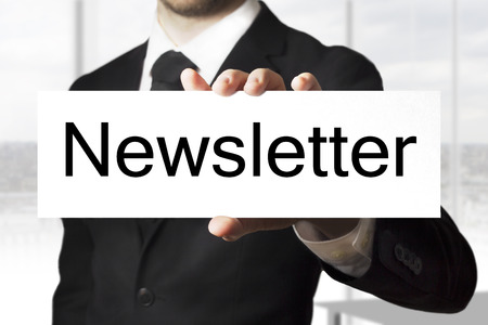 Businessman in black suit holding white sign newsletter